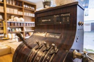 Antique cash register in a shop with ceramics and wooden shelves in the background, Calw Tannery