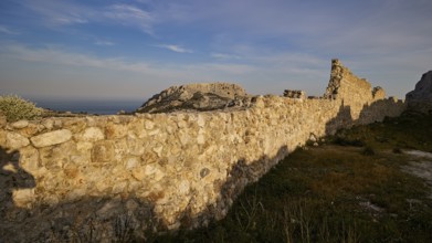 Long, stony wall of ruins stretching across the landscape under a blue sky, Archangelos, castle,