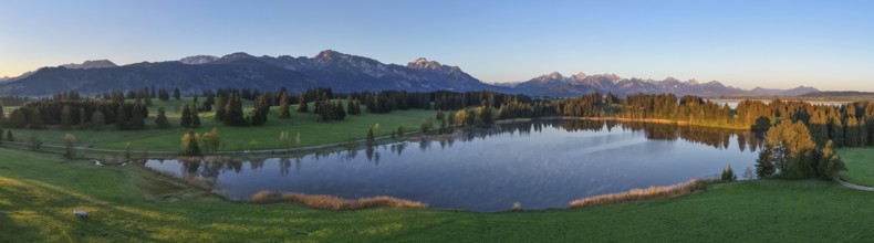 Panoramic view of a lake with mountains and forests at dawn, Hergratsrieder See, Alps, near Füssen,