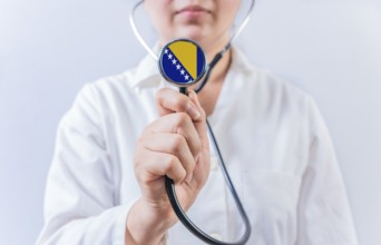 Female doctor holding stethoscope with Bosnia flag. National health system of Bosnia