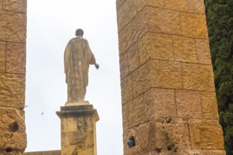 Ancient roman statue standing tall amidst the ruins of tarragona, showcasing the city's rich