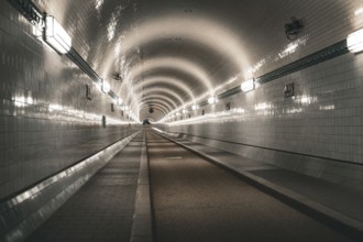 Symmetrically illuminated tiled tunnel with curved lines and depth, old Elbe tunnel, Hamburg,