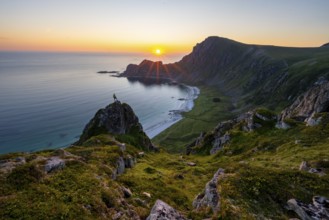 Climber on rocks in front of picturesque landscape, view of coastal landscape at sunset, cliffs and