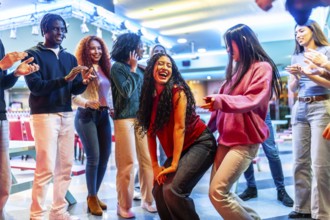 Young diverse friends dancing and having fun at a bowling alley, enjoying their weekend together