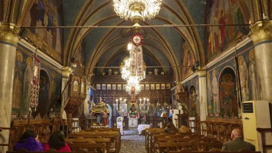 Interior of a church with paintings and chandeliers, people sitting in the pews, Easter fire