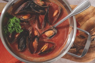 Mussels in tomato sauce, in a silver dish, on a wooden board, rustic style, no people, top view