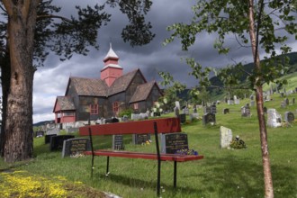 Red bench in front of church and cemetery under a gloomy sky, Dovre church, Dovre kyrkje, Dovre,