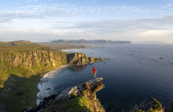 Evening mood, mountaineer standing on a rocky outcrop on the summit of Måtind, view of coastal
