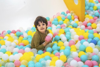 Young boy enjoying playtime in a vibrant ball pit, surrounded by colorful plastic balls in a lively