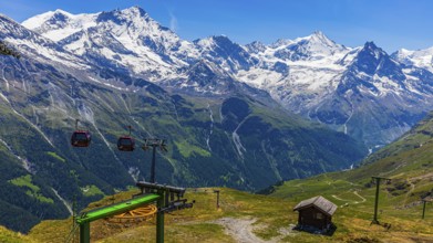 Gondolas of the cable car from Zinal to Corne de Sorebois, behind the snow-covered peaks Weisshorn,