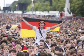 Football fan on shoulders with German flag in the fan zone at the Brandenburg Tor during the