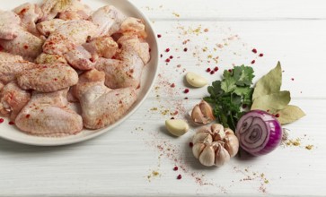 Fresh, raw chicken wings, with spices, on a white wooden table