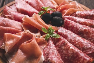 Assortment, sliced meat appetizer, prosciutto, salami and ham, with olives, breakfast, top view,