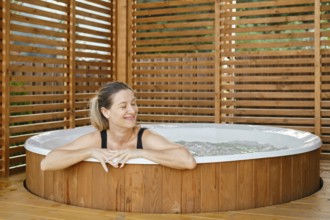 Portrait of carefree happy smiling woman relaxing at outdoor hot tub during her vacation