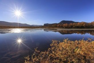 Mountains reflected in lake, autumn colours, sun, sun star, bright, friendly, Nikkaluokta, Laponia,