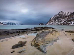 Rocks on Haukland beach, snow-capped mountains in the background, Vestvågøya, Lofoten, Norway,