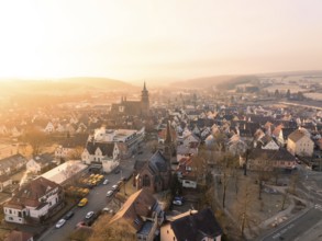 A village with a church tower, surrounded by hills and trees, in the warm light of the sunset, Weil