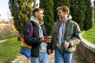 Happy gay couple holding hands and walking in a park, enjoying a relaxing day together and showing
