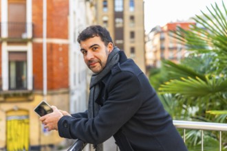 Portrait of a casual businessman smiling at camera leaning on a rail relaxed on a work break in the