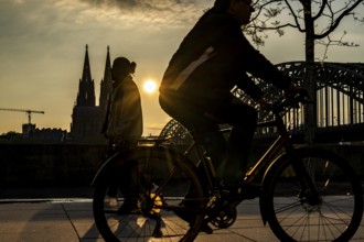 Silhouettes of people in late sunlight, on the Deutz riverbank, right bank of the Rhine, cyclists,