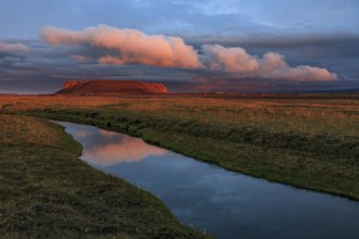 Volcanic crater reflected in stream, lava field, cloudy mood, midnight sun, summer, Burfellshraun,