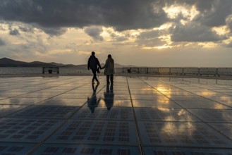 Couple on the solar installation Greeting to the sun at sunset, Zadar, Croatia, Europe