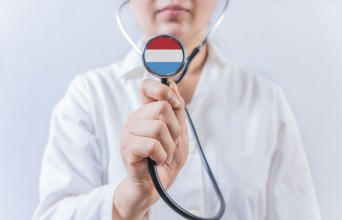 Female doctor holding stethoscope with Luxembourg flag. National health system of Luxembourg