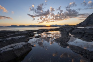 Clouds reflected in a small pond on a rocky coast, coastal landscape at sunset, Henningsvær,