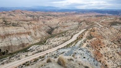 Track leads through wide, hilly desert landscape with dry vegetation, Gorafe desert, semi-desert,