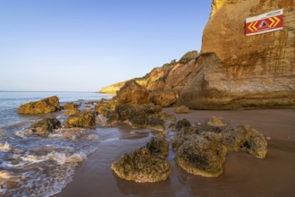 ROCKFALL UNSTABLE CLIFFS, KEEP A SAFE DISTANCE is written in English on a warning sign in Portugal
