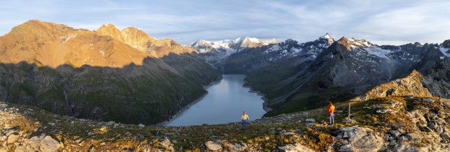 Hikers enjoying the alpine panorama at Lac de Dix, sunset in the mountains, reservoir, Valais Alps,