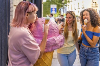 Girls having fun eating ice cream in the city standing in front of ice cream store with a giant