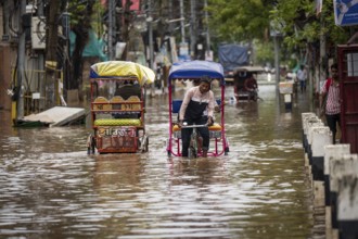 Commuters in cycle rickshaws as they wade through a flooded street after heavy rains in Guwahati,