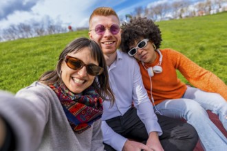 Three cheerful friends are taking a selfie in a park, enjoying a sunny spring day together