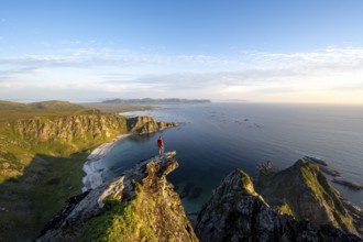 Evening mood, mountaineer standing on a rocky outcrop on the summit of Måtind, view of coastal