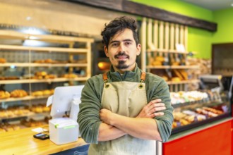 Portrait of a confident latin young baker standing with arms crossed in an artisan modern shop