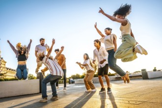 Full length photo of a group of multiracial friends jumping and dancing in the city during sunset