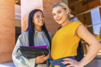 Caucasian and chinese female university students smiling at camera and standing outside the