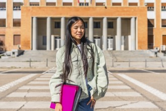 Portrait of a confident chines university student standing in the street at the entrance of the