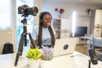Young female content creator smiling and recording video with professional equipment in her living
