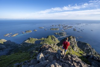 Mountaineer on the summit of Festvagstinden, view of the sea and archipelago islands with the