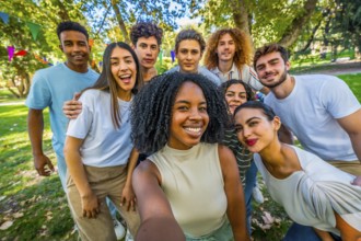 Happy african woman taking selfie with multi-ethnic friends in park during a celebration