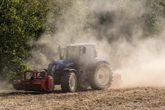 Tractor with plough digging up dried-out soil, large cloud of dust, dust, dry, field, soil,