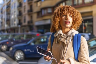 Beauty young latin woman listening to music using headphones and smartphone standing in the street