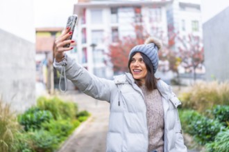 Beauty woman in winter clothes taking selfie with mobile phone in the city