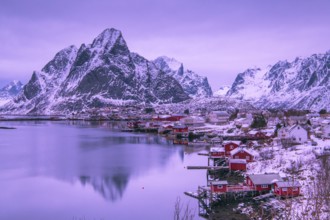 Fishermen's Village in front of snowy mountain range at the coastline in winter, Lofoten, Norway,