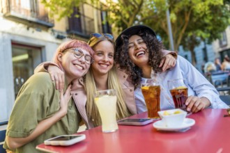 Happy female friends meeting on a bar terrace enjoying sunset at city