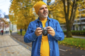 Mature man in urban clothes photographing a city while visiting in autumn