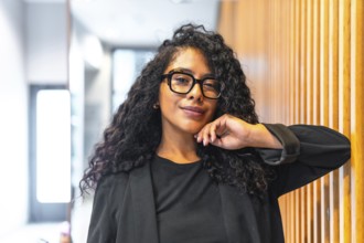 Portrait of a confident and cheerful latin businesswoman with long curly hair and formal elegant