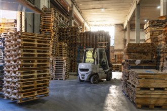 Full length photo with no people of a forklift in a pallet storage room in a recycling plant